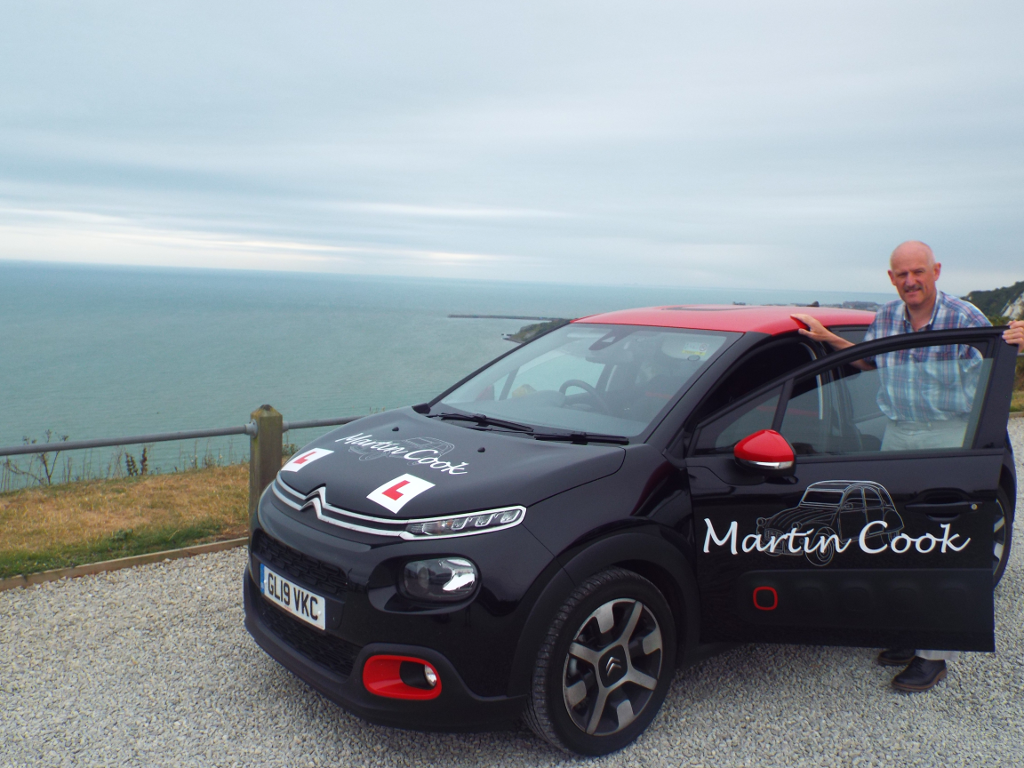 Martin Cook beside his driving instructor car